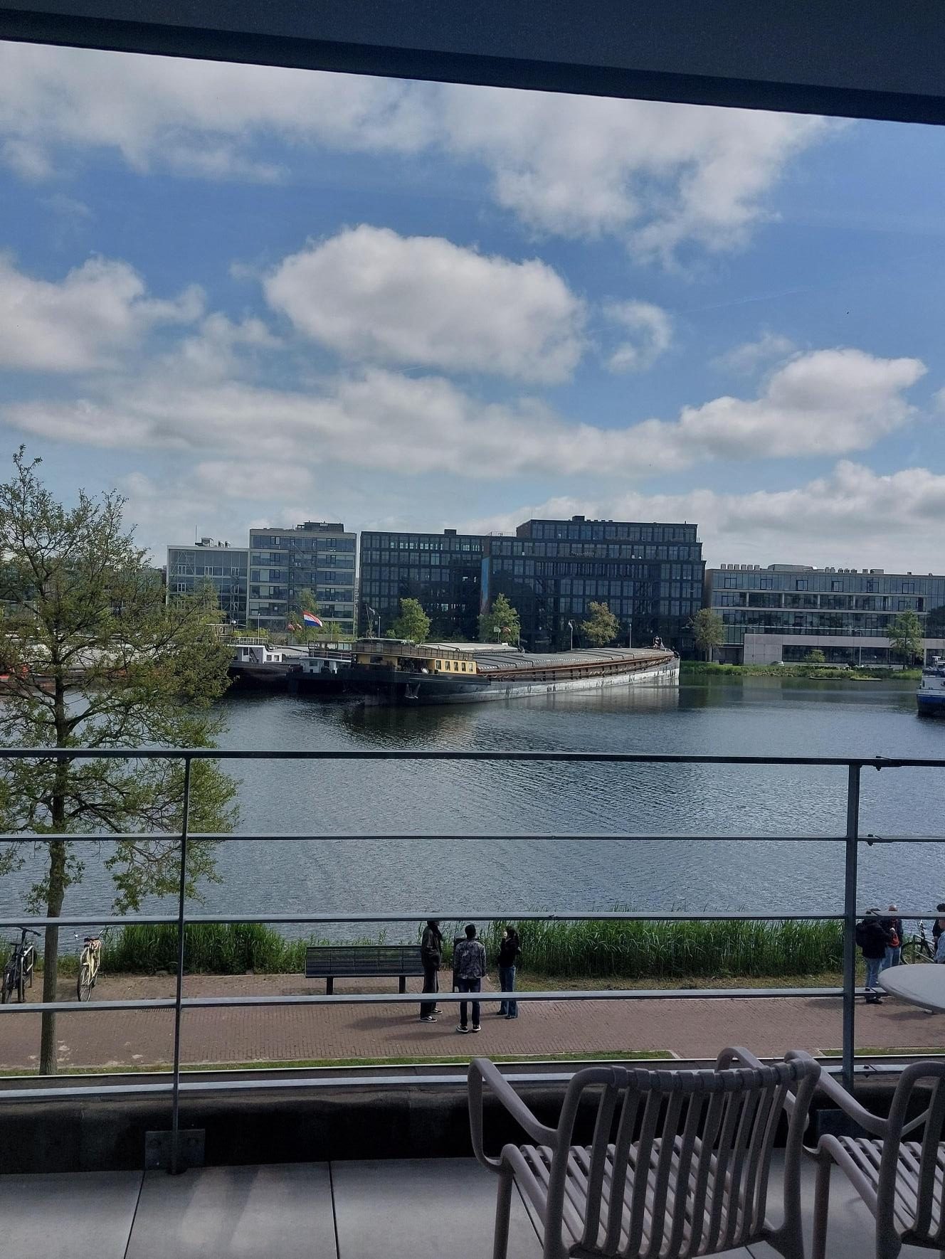 A canal on a sunny day seen through a glass railing