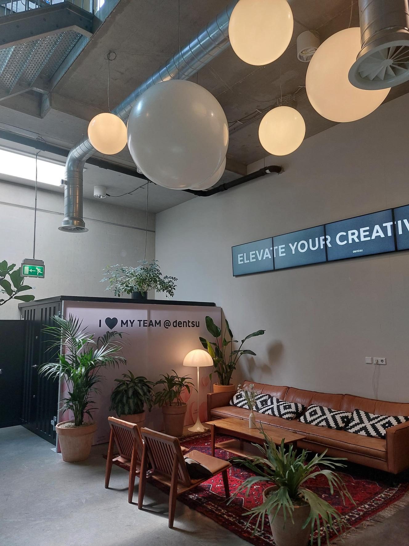 A lounge corner with plants and large round pendant lights